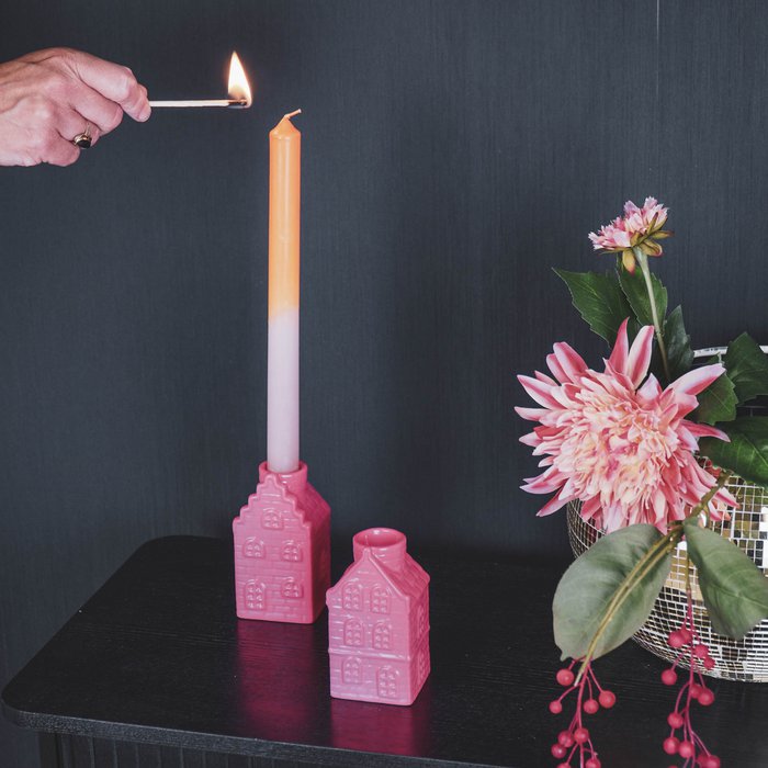 Felroze kandelaars in de vorm van Amsterdamse huisjes. 